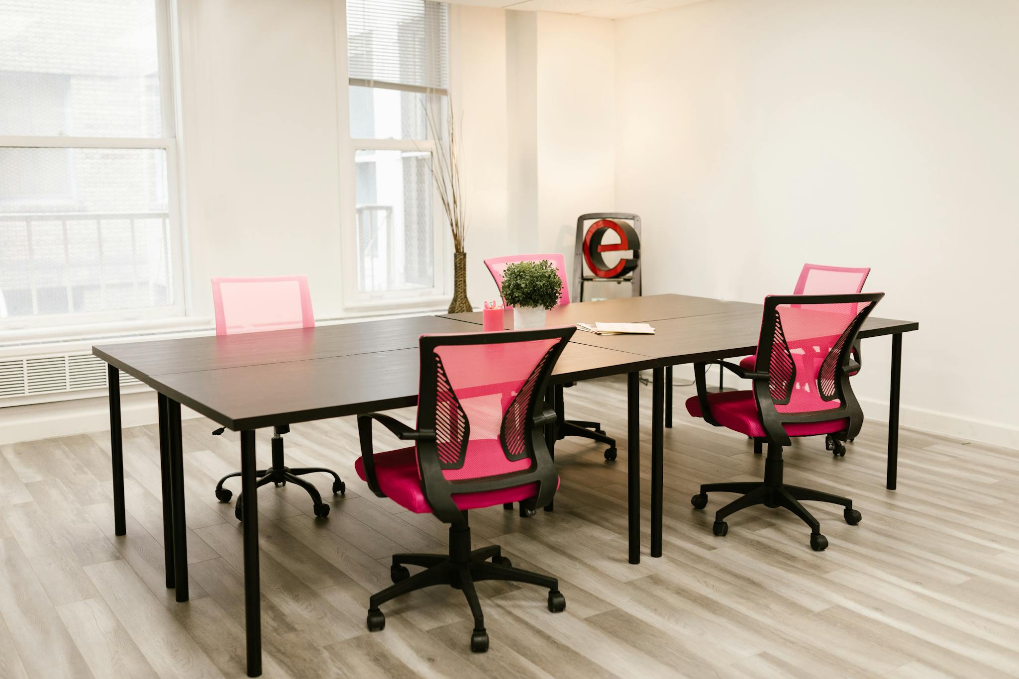 Modern office space featuring pink ergonomic chairs around a sleek conference table.