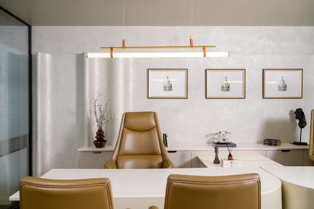 A stylish office space with leather chairs, art on the walls, and modern lighting.
